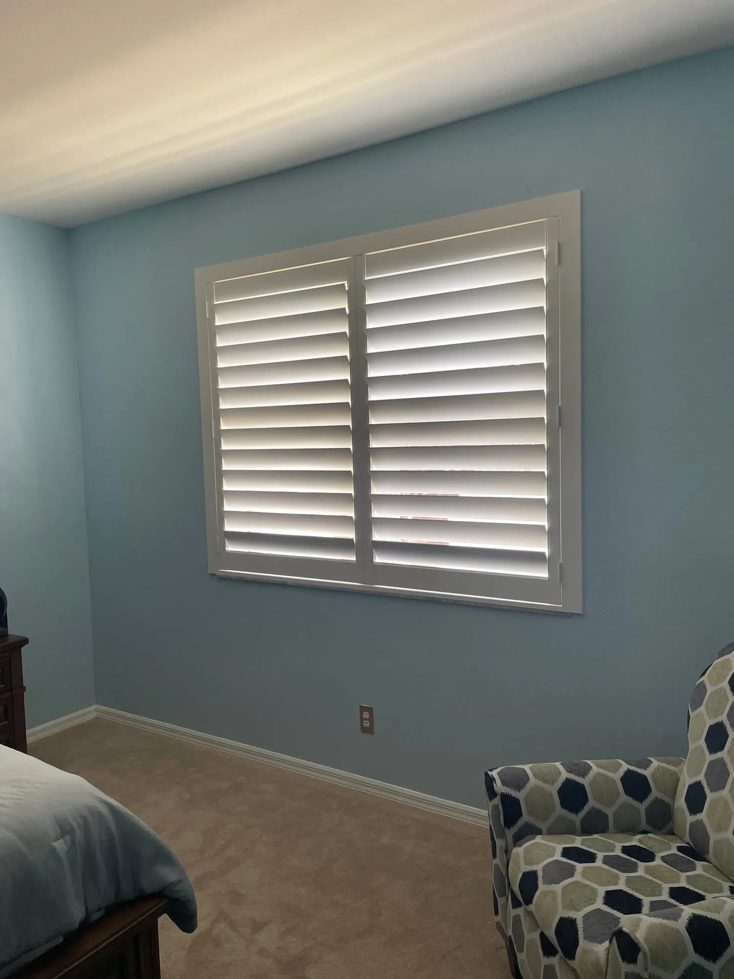 Mid-rail shutter letting light in above and holding privacy below in a pale blue bedroom