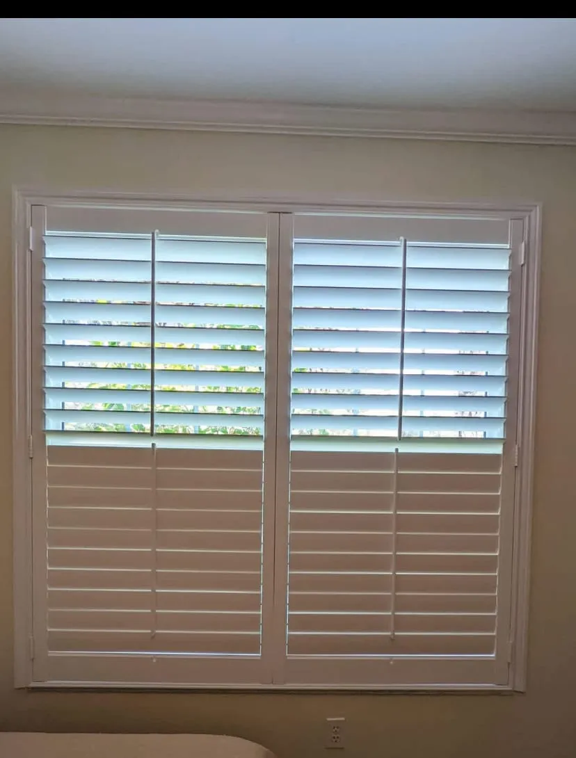 Wide two-panel shutter over a bedroom window with the top louvers open to the garden