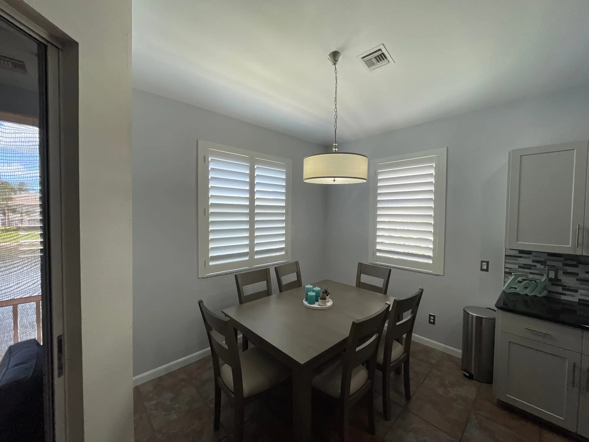 Two full-height white plantation shutters in a Southwest Florida dining nook