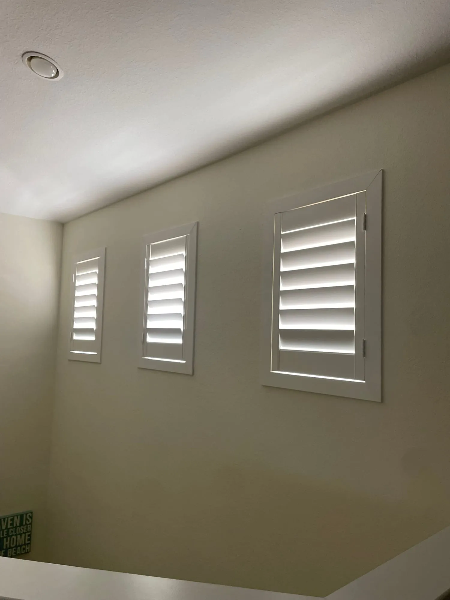 Three stacked shutters running up a stairwell wall